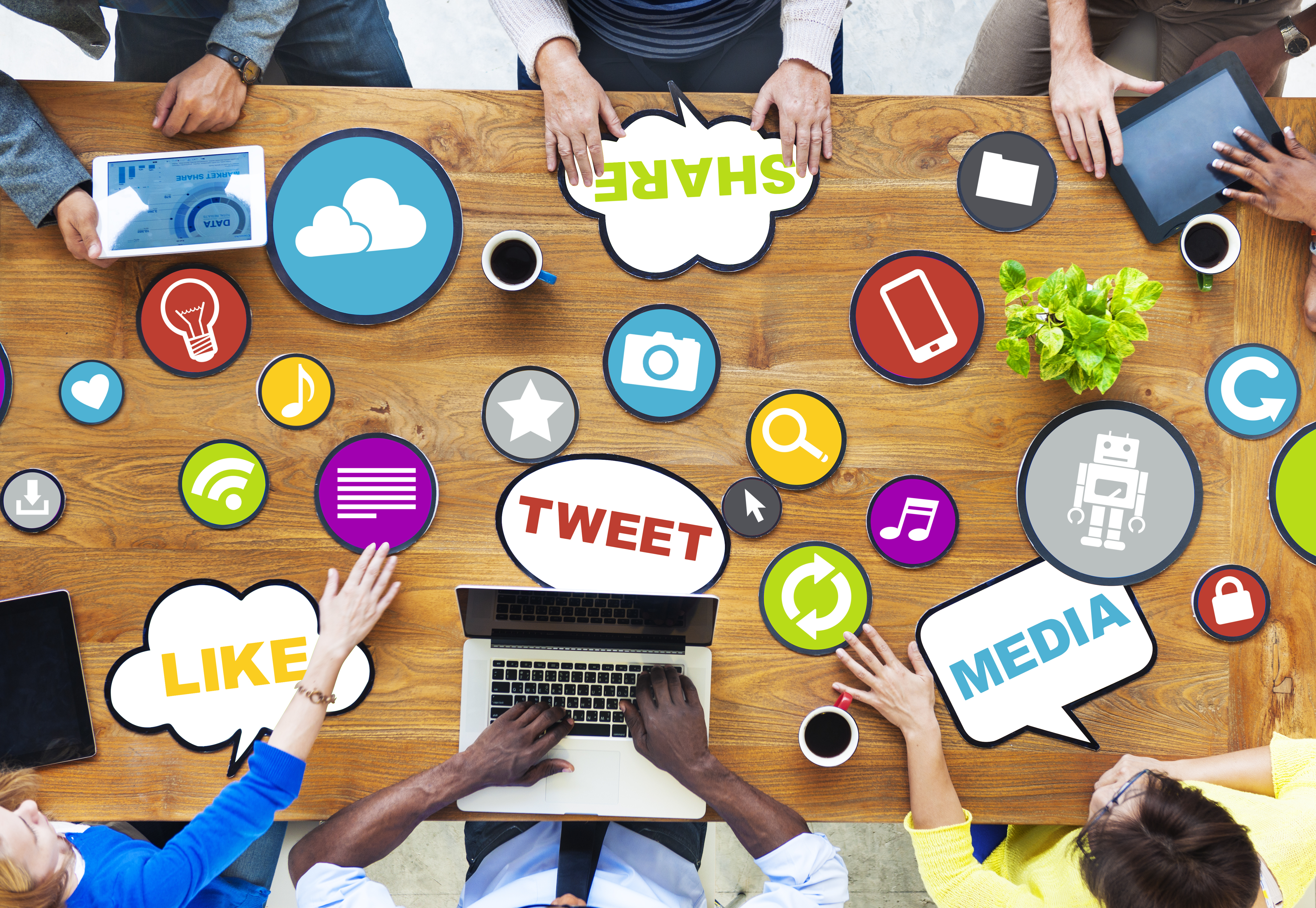 Group of people accessing various social media platforms across a table